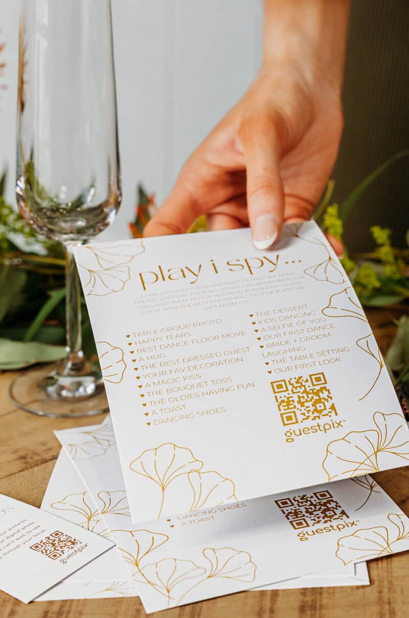 Una mano elegante sostiene una tarjeta con un código QR inspirada en una boda, perteneciente a la nueva colección nupcial, que destaca por sus detalles florales y sus elementos de diseño moderno.