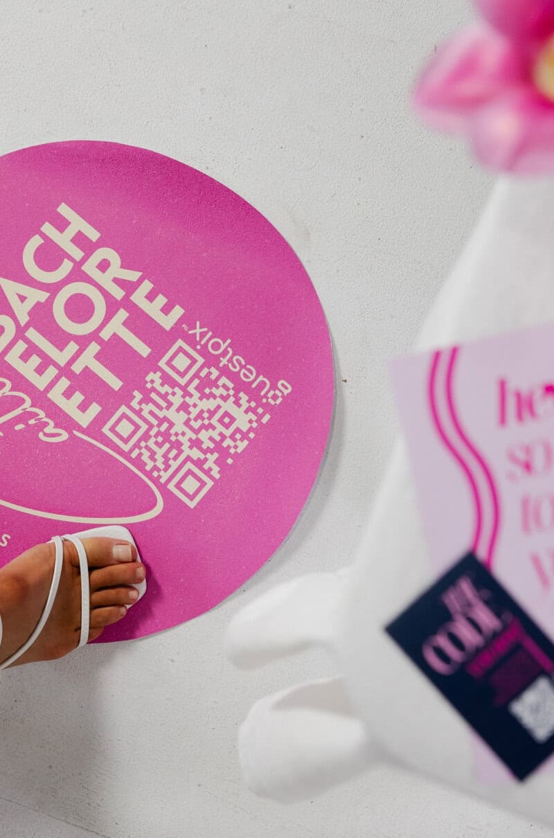 Cartello rotondo rosa con codice QR e la scritta "Beach Party", che invita a condividere le foto dell'evento durante una festa a tema spiaggia.