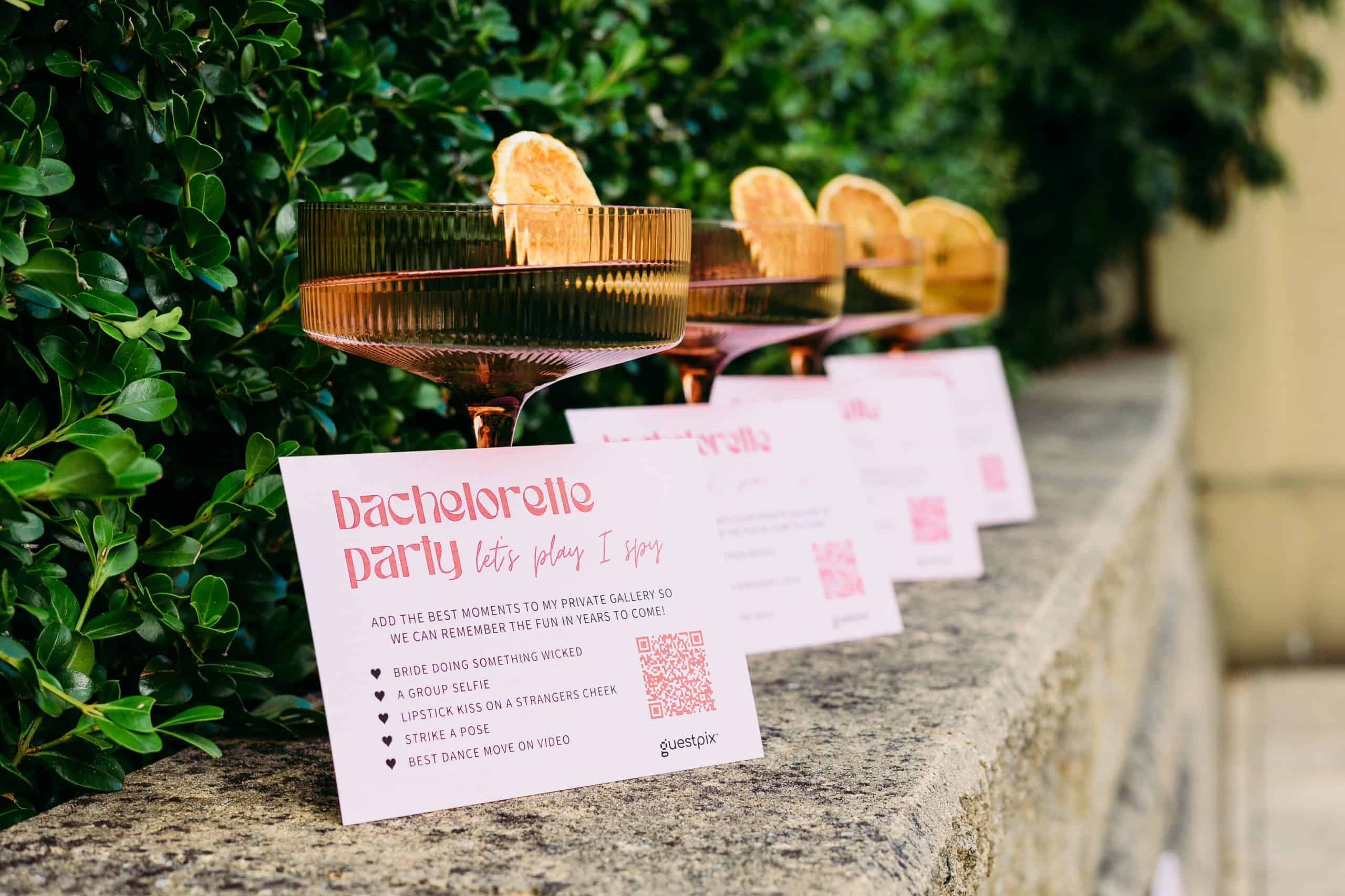 Una fila di volantini rosa con la scritta “addio al nubilato” appoggiati su una sporgenza di pietra accanto a un arbusto verde.
