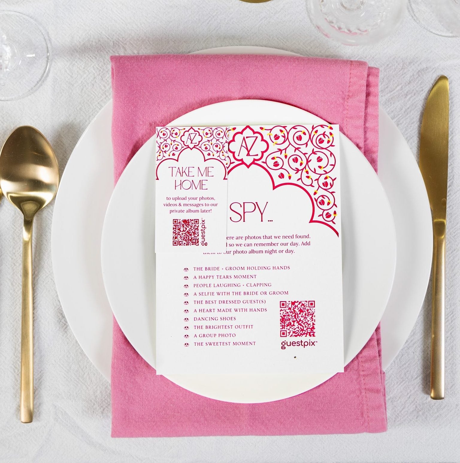 GUESTPIX December 2023 2 - GUESTPIX | #1 QR Code Event Photo Sharing Platform Top-down view of a formal table setting with a white plate, pink napkin, gold utensils, crystal glasses, and a pink invitation card on the plate (says 'Take Me Home').
