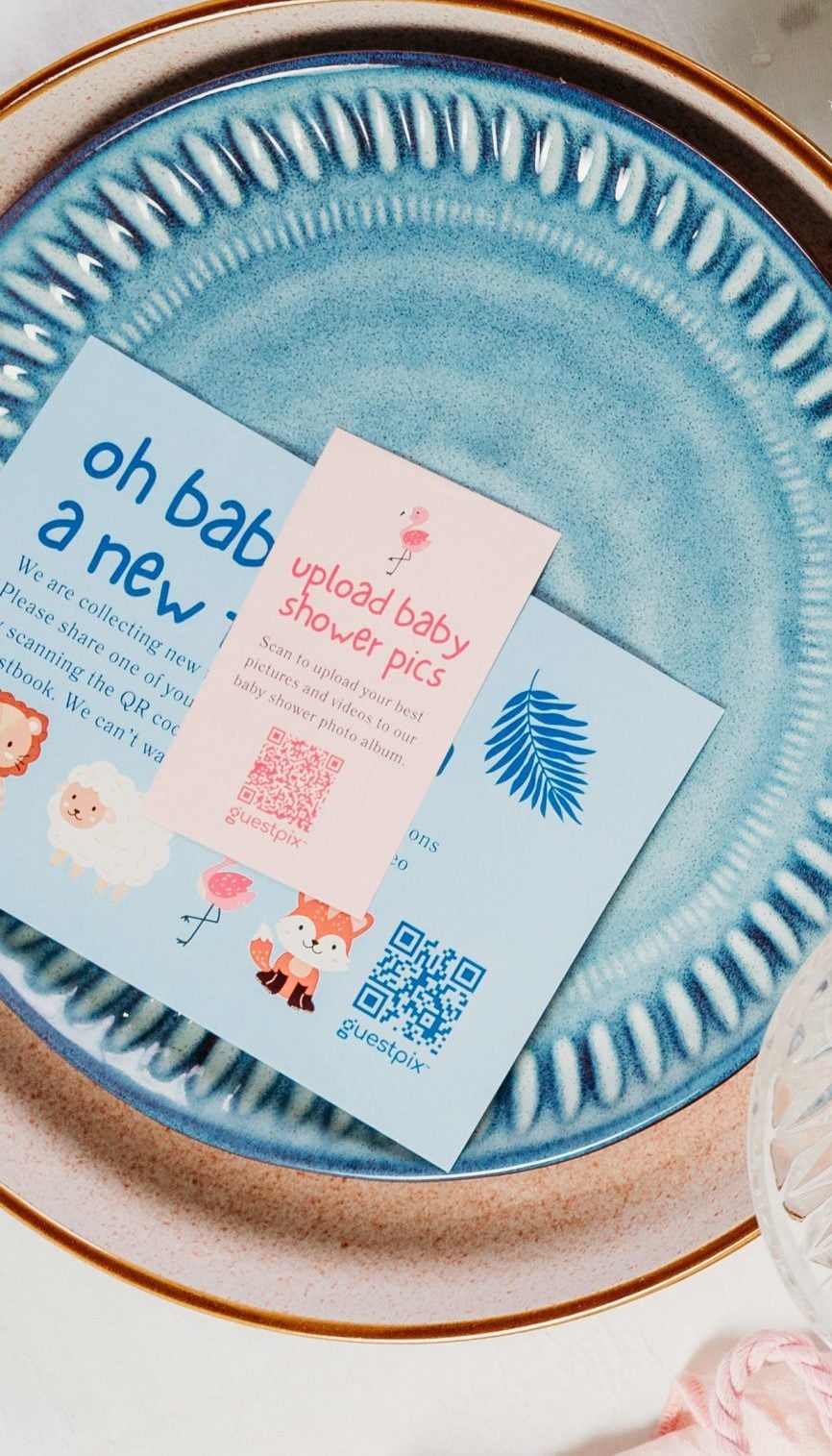 GUESTPIX December 2023 234 - GUESTPIX | #1 QR Code Event Photo Sharing Platform Blue ceramic plate with baby shower invitations and a spray of white baby's breath on a white table.