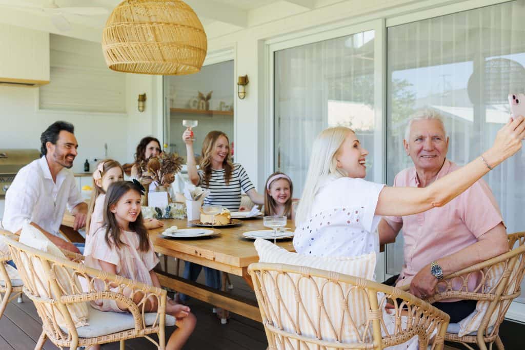 Une famille profitant d'une fête, prenant un selfie tous ensemble dans un intérieur lumineux et moderne, en compagnie d'amis et d'enfants.