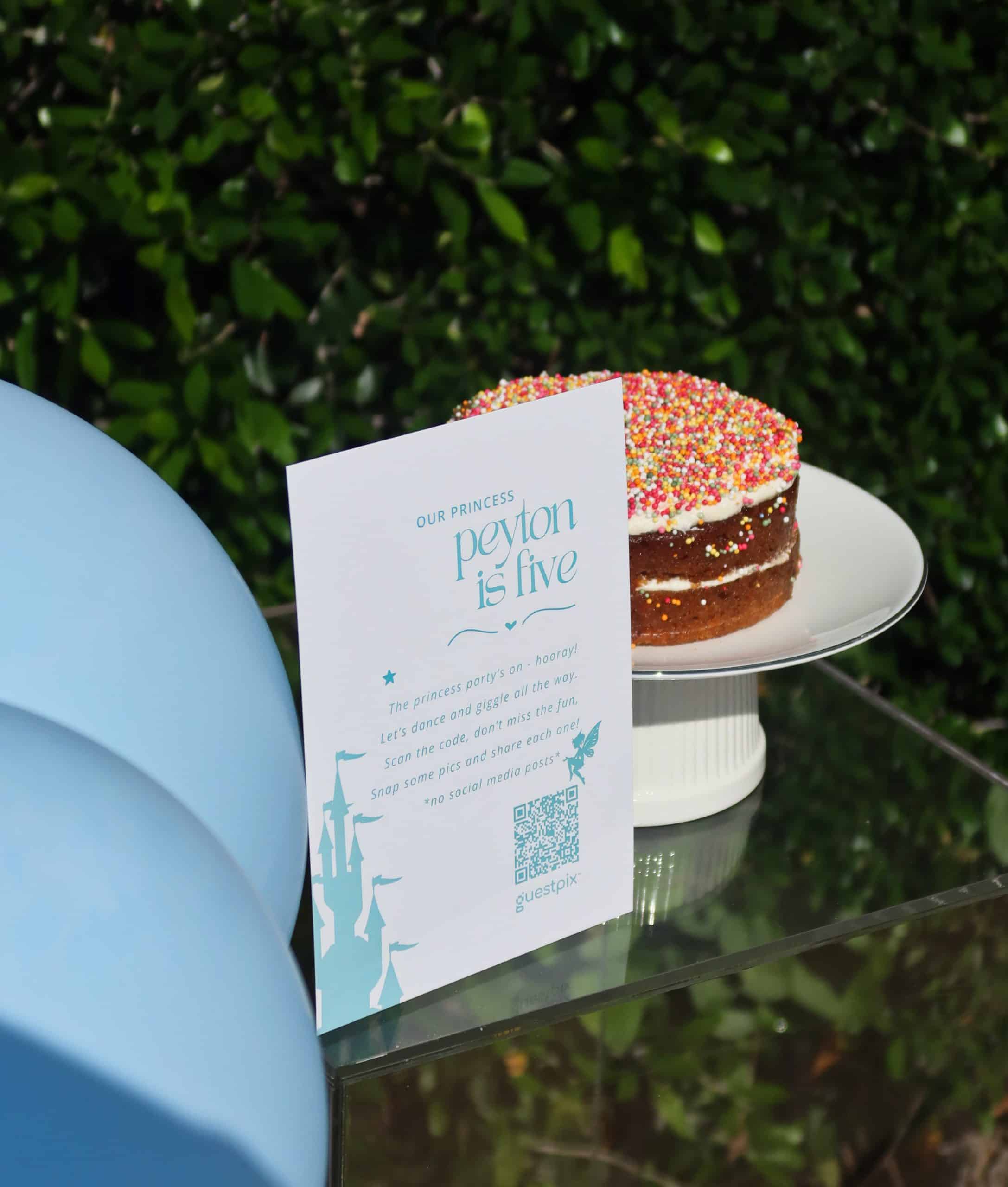 Tarta de celebración con virutas de colores y una tarjeta de invitación con temática de princesas en una fiesta infantil.