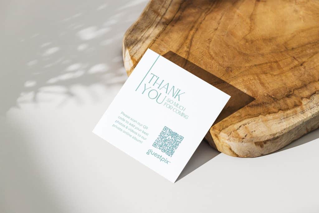 Tarjeta de agradecimiento sobre una superficie de madera con un código QR de color verde azulado y un mensaje de felicitación.