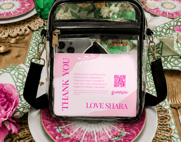 Sachet transparent dans lequel on aperçoit une carte rose portant l'inscription « THANK YOU » et le message « LOVE SHARA », posé sur une table colorée et fleurie avec des assiettes et des couverts (cadeau de bienvenue lors d'un événement).