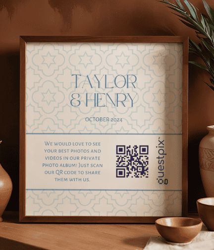 Cartel enmarcado colgado en una pared marrón en el que se anuncia el evento de Taylor &amp; Henry de octubre de 2024, con un motivo geométrico de color turquesa y un código QR para compartir fotos.