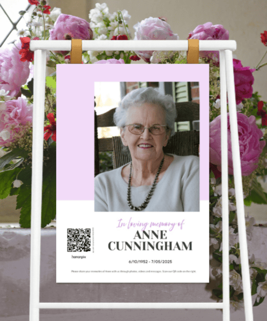 Cartel conmemorativo colocado en un caballete con un retrato de Anne Cunningham, detalles en color lavanda, las fechas de nacimiento y fallecimiento y un código QR.