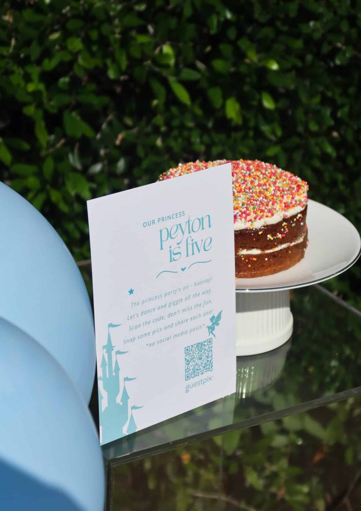 Eine Festtorte mit bunten Streuseln und einer Einladungskarte im Prinzessinnen-Stil auf einer Kinderparty.