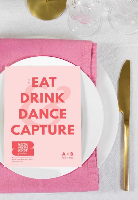 A colourful event menu card with the words "Eat, Drink, Dance, Capture" and a QR code, placed on a white plate with pink napkin, gold cutlery, and glassware.