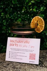 Une photo présentant une décoration pour un enterrement de vie de jeune fille, avec un verre à cocktail orné d'une rondelle d'orange séchée et une carte « Guestpix », faisant la promotion de la nouvelle suite « enterrement de vie de jeune fille » disponible en plusieurs motifs.