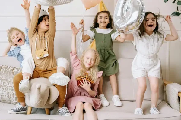 Joyful kids celebrating birthday with balloons, gifts, and party hats at a lively indoor event. Exciting moments captured of children enjoying party activities and colourful decorations.