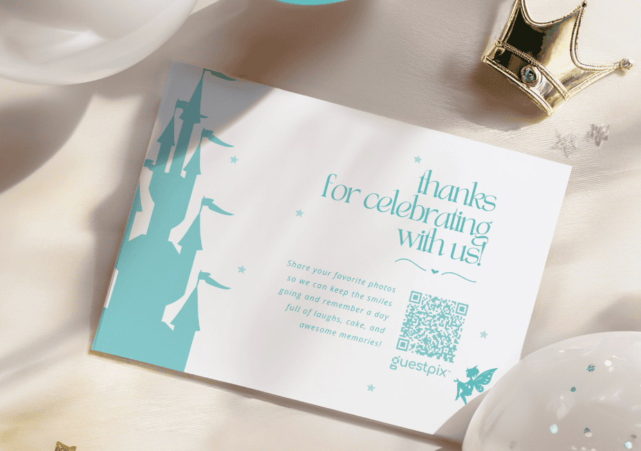 Il biglietto di ringraziamento recita "Grazie per aver festeggiato con noi!" su un'illustrazione di un castello color verde acqua con un codice QR accanto, appoggiato su un tavolo luminoso accanto a un ornamento a forma di corona.
