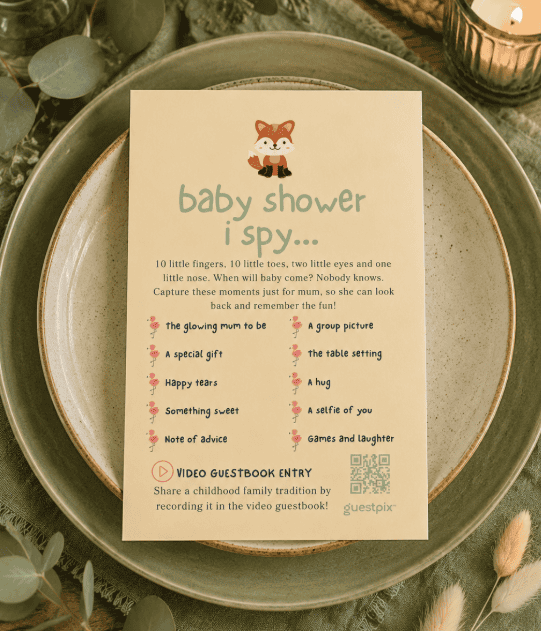 Biglietto con attività per baby shower intitolato “Baby shower I Spy” su un piatto verde con candeline e foglie sullo sfondo