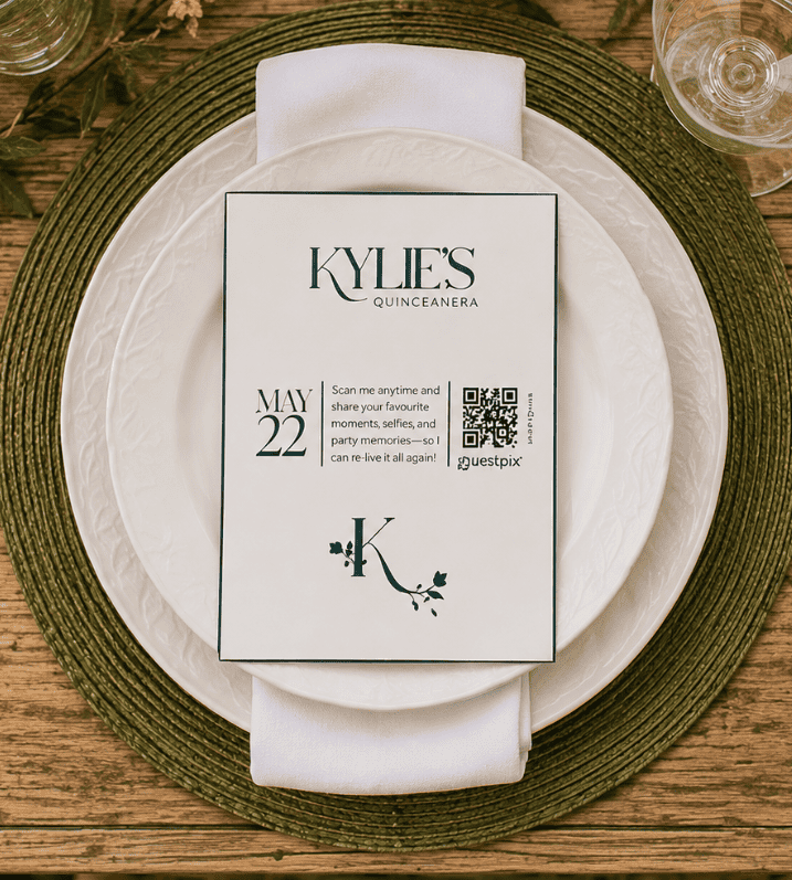 Carte d'invitation pour la quinceañera de Kylie, posée sur une assiette blanche avec une serviette et un set de table vert ; elle indique la date du 22 mai et comporte un code QR.