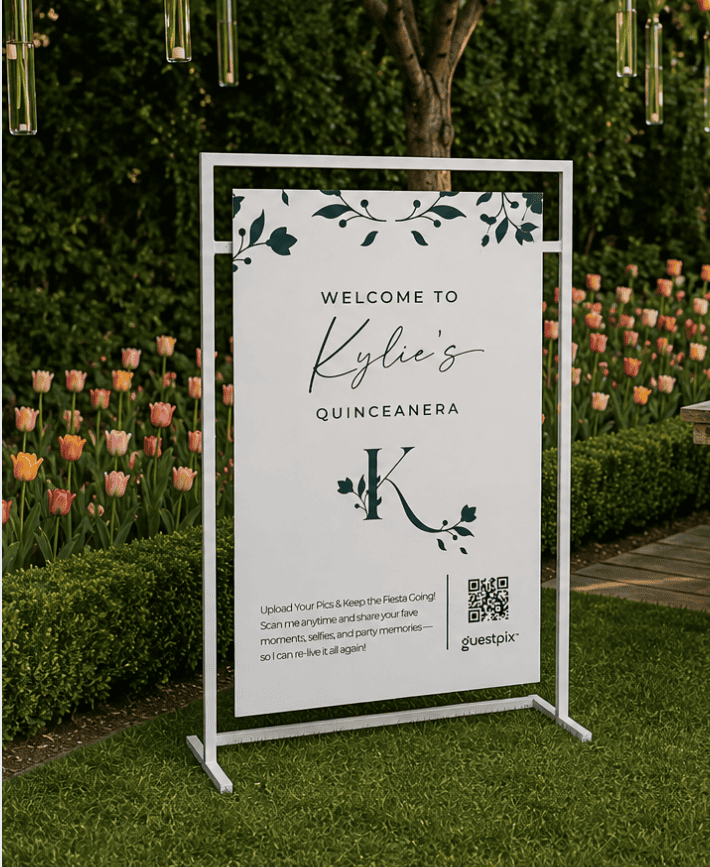Panneau portant l'inscription « Bienvenue à la quinceañera de Kylie », orné de feuillage décoratif et d'une grande initiale « K », installé à l'extérieur au milieu des tulipes ; il comporte un code QR.