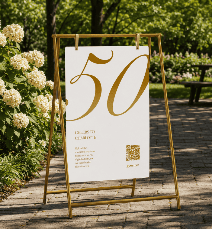 Panneau de jardin annonçant la célébration du 50e anniversaire : un grand « 50 » doré accompagné de la mention « Cheers to Charlotte » et d'un code QR sur un panneau blanc.