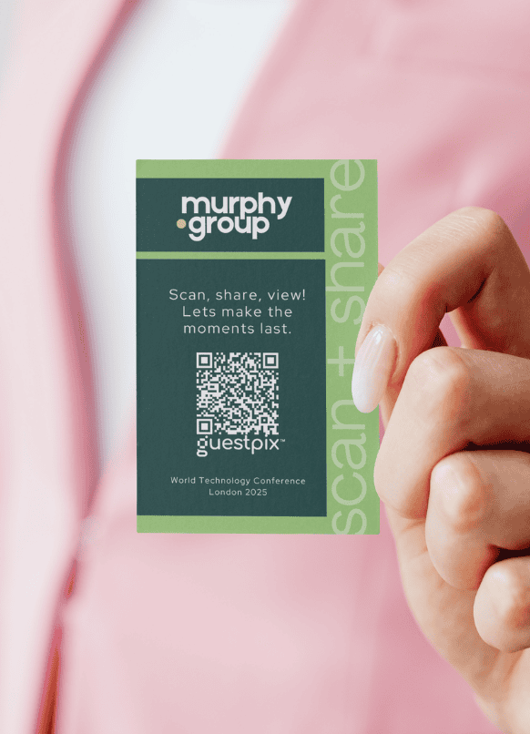 Zwischen den Fingern gehaltenes Konferenz-Namensschild mit einem QR-Code und dem Logo der Murphy Group; darauf steht: „Scannen, teilen, ansehen! Lassen wir die Momente in Erinnerung bleiben.“ Für die World Technology Conference London 2025.