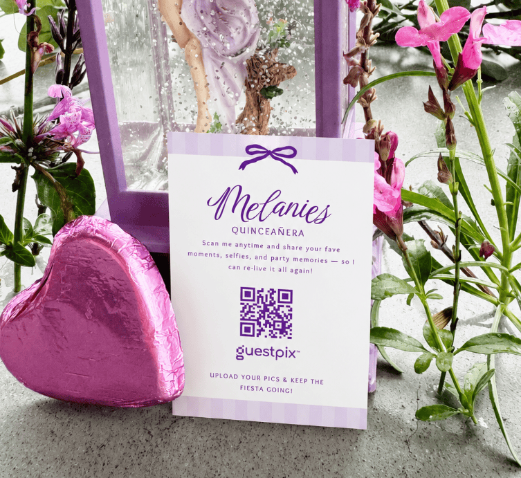 Sur la carte d'invitation à la quinceañera, on voit Mélanie, avec à côté un ballon en forme de cœur rose et des fleurs violettes qui encadrent un cadre rehaussé de touches violettes.