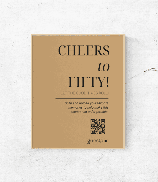 Manifesto beige su una parete chiara con la scritta “CHEERS to FIFTY!” e “LET THE GOOD TIMES ROLL!”, una riga orizzontale di testo, un codice QR e il logo di Guestpix.