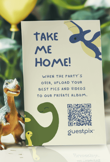Auf der Karte steht „TAKE ME HOME!“, womit die Gäste dazu eingeladen werden, Fotos und Videos in ein privates Album hochzuladen; zu sehen sind ein QR-Code, Comic-Dinosaurier, ein gelber Luftballon und ein Spielzeugdinosaurier im Vordergrund.