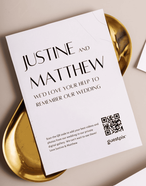 Biglietto d'invito al matrimonio di Justine e Matthew su un vassoio dorato, con un codice QR e il testo per la conferma di partecipazione.