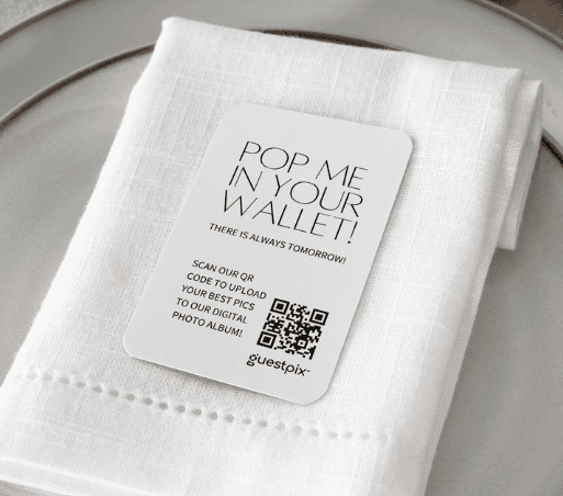 Biglietto promozionale appoggiato su un tovagliolo bianco piegato, posto sopra un piatto, con la scritta “Mettimi nel tuo portafoglio!” e un codice QR da scansionare.